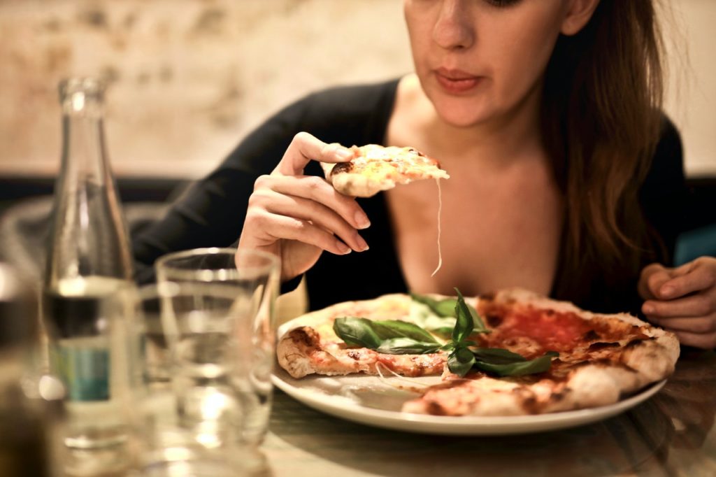 une femme tient des tranches de pizza près d'une table avec du verre