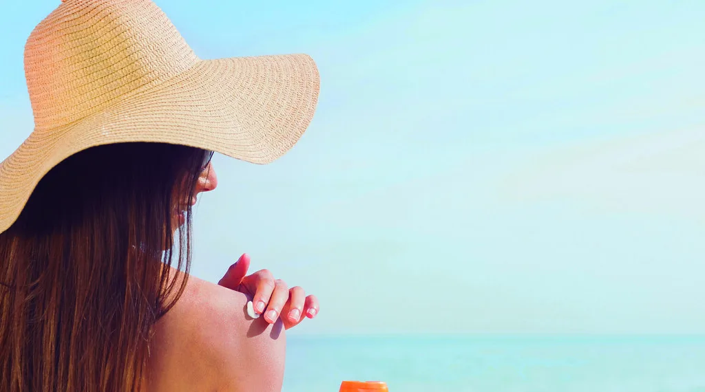 Brunette putting sunscreen on her shoulder