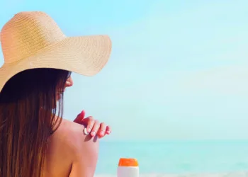 Brunette putting sunscreen on her shoulder