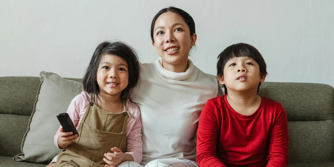 Positive mother with daughter and son watching cartoon on TV