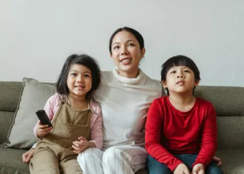 Positive mother with daughter and son watching cartoon on TV