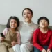 Positive mother with daughter and son watching cartoon on TV