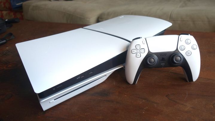 A PS5 sits on a table with a DualSense standing next to it.