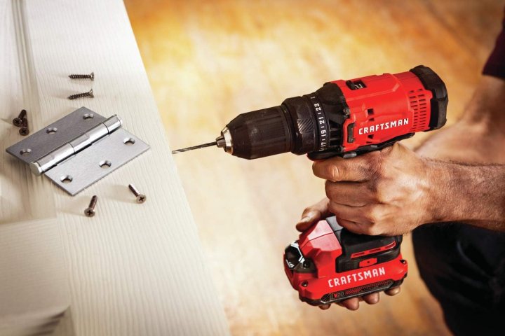 A person using a Craftsman V20 Drill/Driver on a wooden surface.