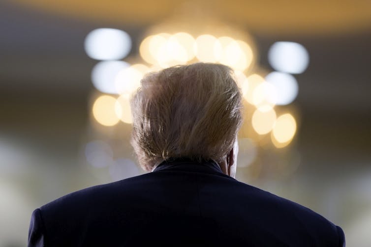 Donald Trump is seen from behind as he speaks to a crowd.