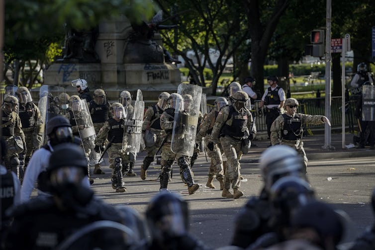 Military personnel walking into a cleared area.