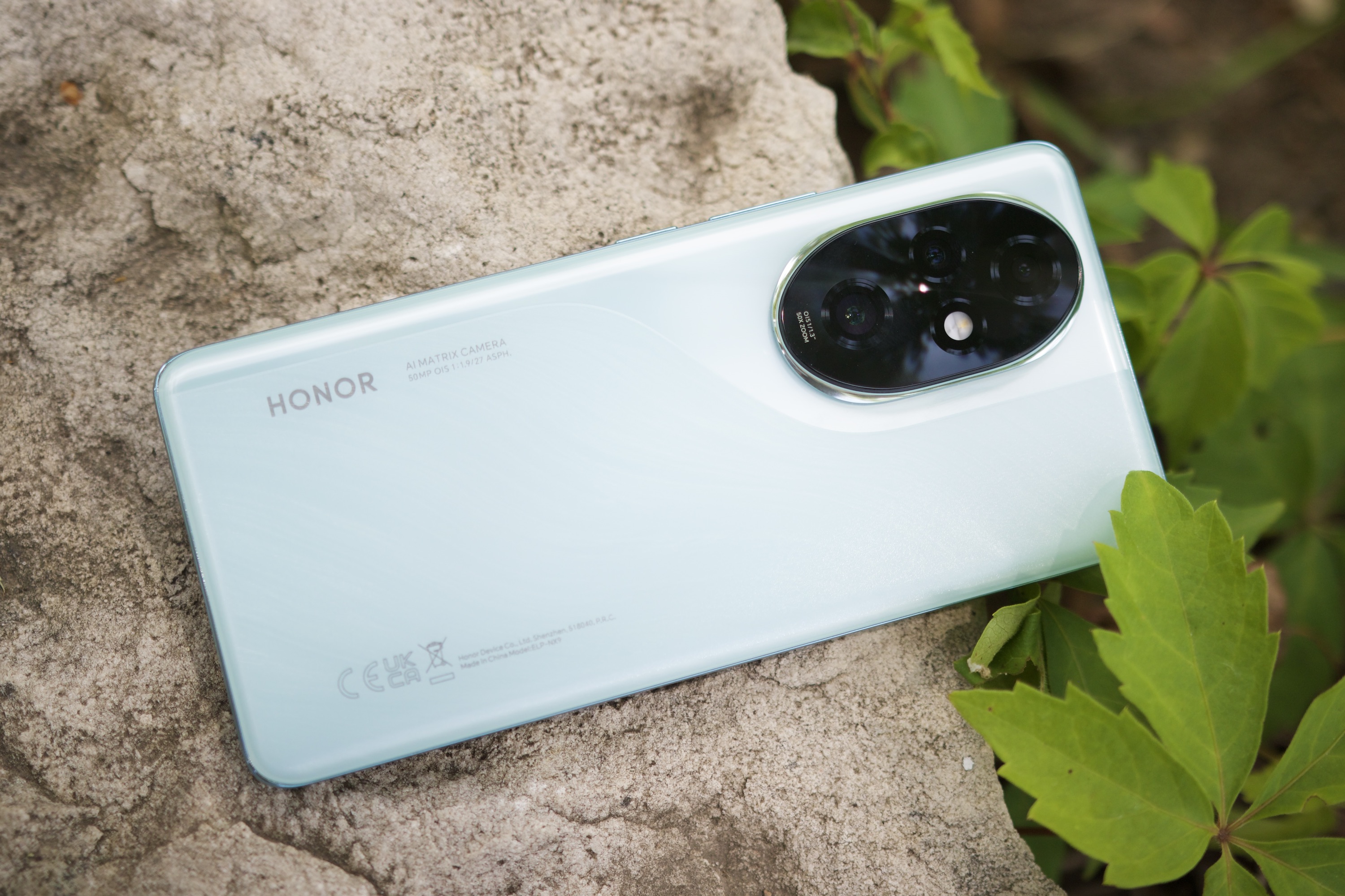 The Honor 200 Pro smartphone resting on a rock outdoors.