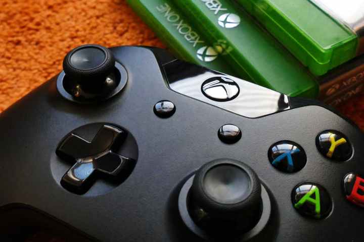 An Xbox controller rests on the floor beside a collection of Xbox One games.