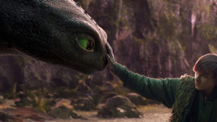 A boy touches the nose of a dragon.