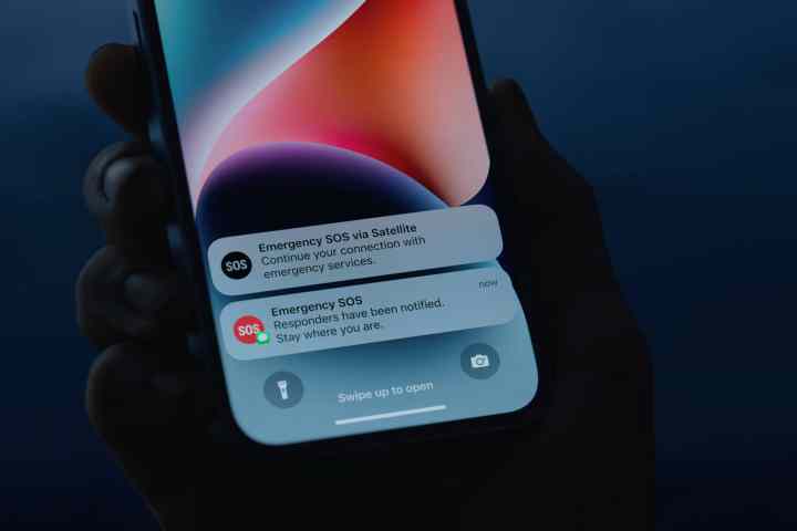 Individual holding an iPhone 14 displaying Emergency SOS via satellite notifications.