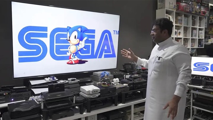 Ibrahim Al-Nasser in front of his console collection with Sonic and the Sega logo displayed on the TV.